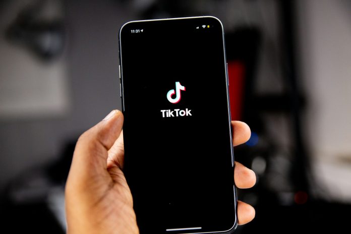 tiktok generico Pessoa segurando smartphone com o aplicativo TikTok aberto na tela.